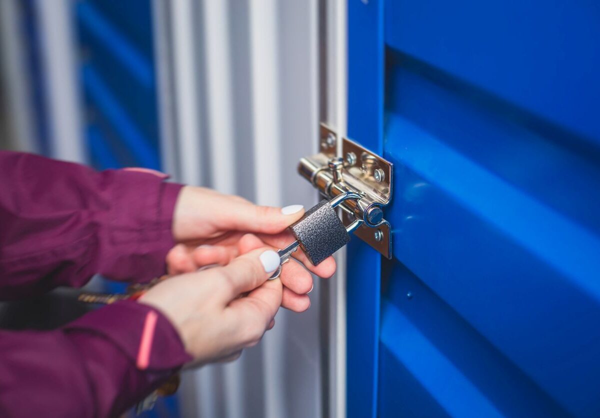 A person locking a blue self storage unit with a padlock