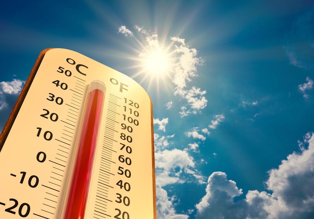 A thermometer set against a backdrop of a blue sky with the sun.