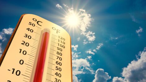 A thermometer set against a backdrop of a blue sky with the sun.