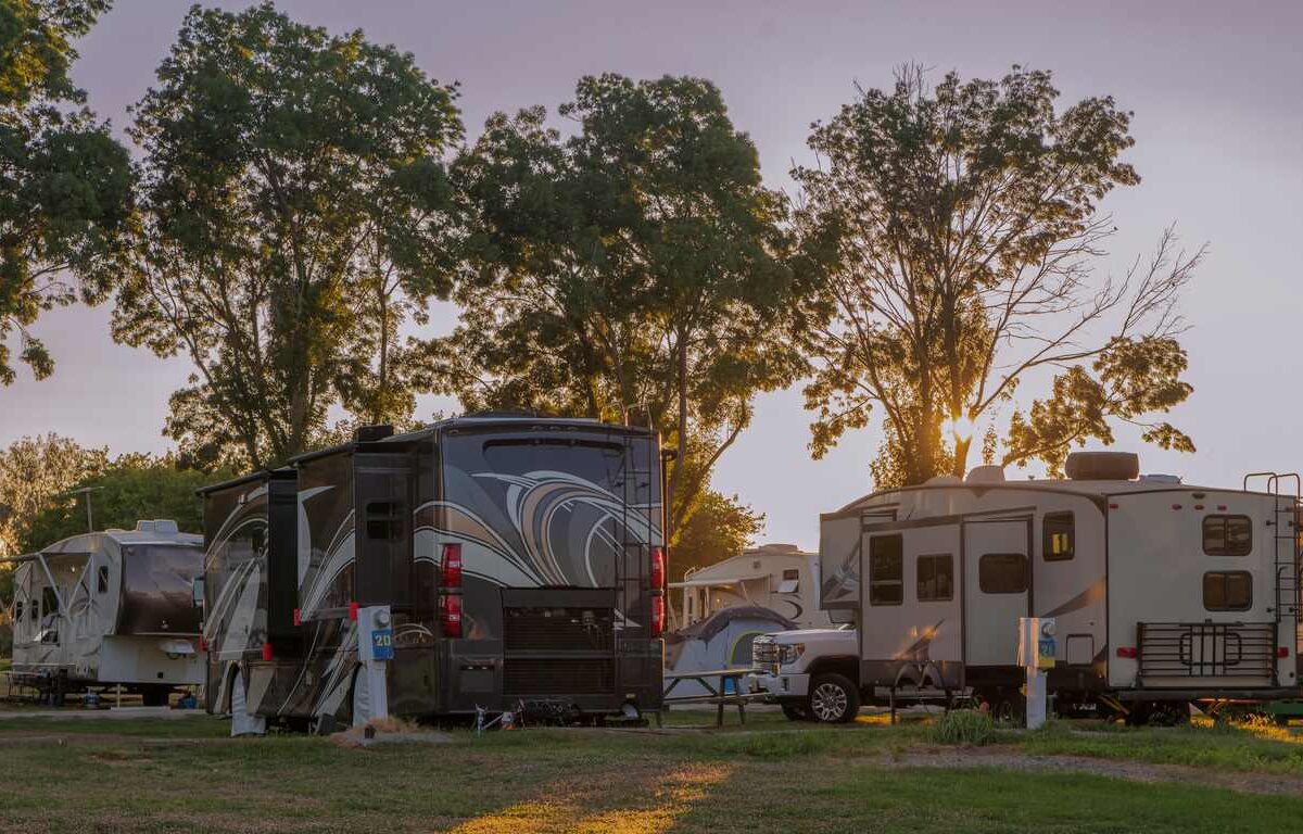 A sunset at an RV park with many motor homes.